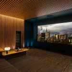 Luxury home theater with a wood-paneled accent wall, recessed lighting, and a large screen displaying a city skyline.